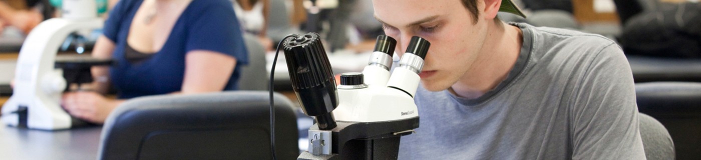 WOU student looking through microscope