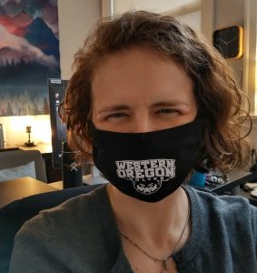 Bev West wearing a a black WOU non-surgical mask in her office