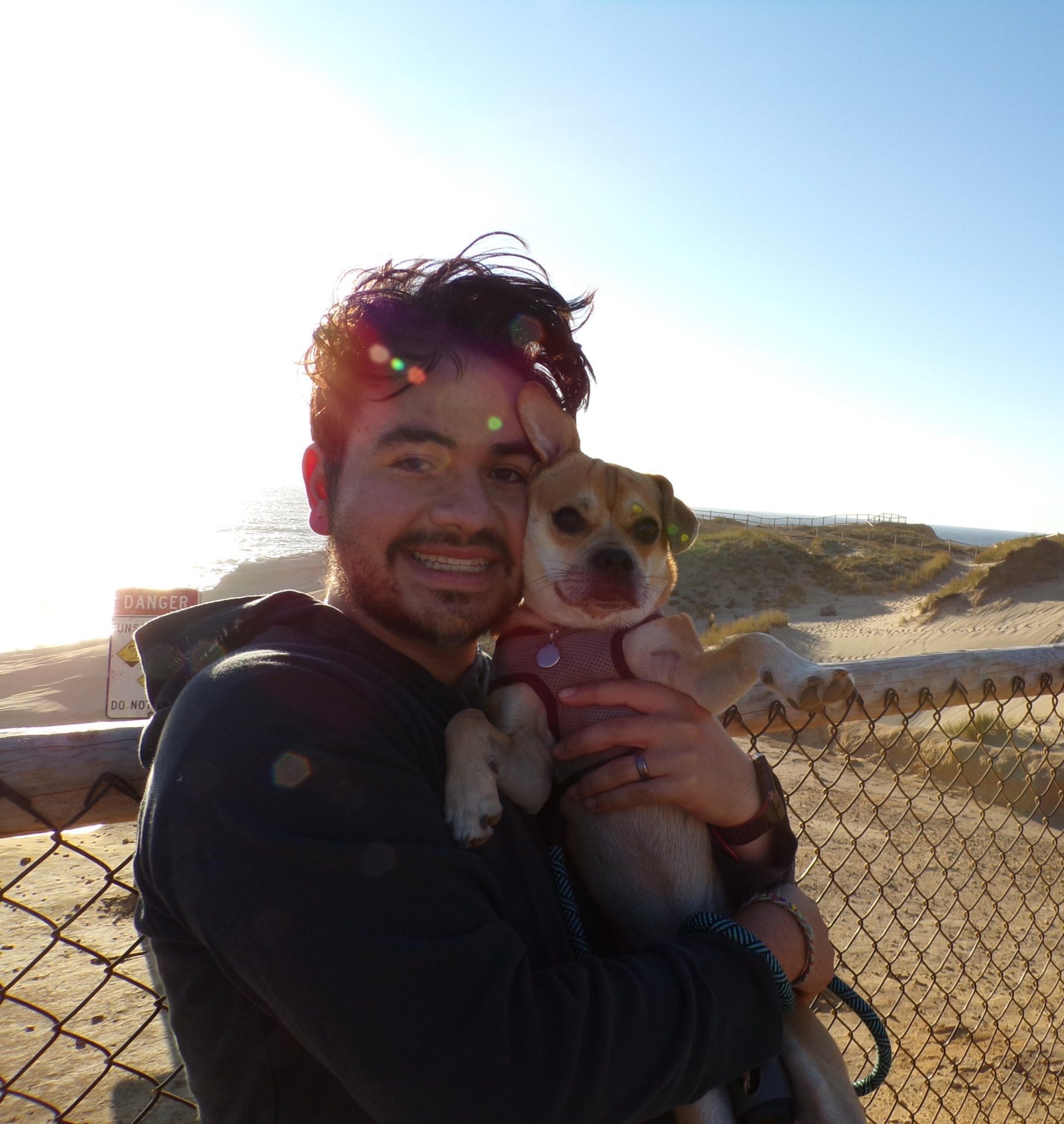 A photo of Andres and his small dog on the beach