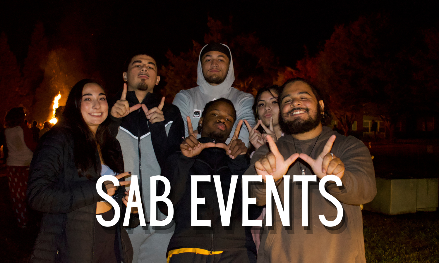 A group of students posed together at a bon fire. Four of the six students are making a W with their hands.  The words "SAB Events" are superimposed over the group.