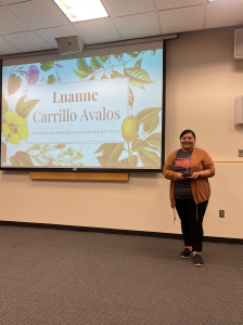 Luanne Carrillo-Avalos holding award in front of projector.