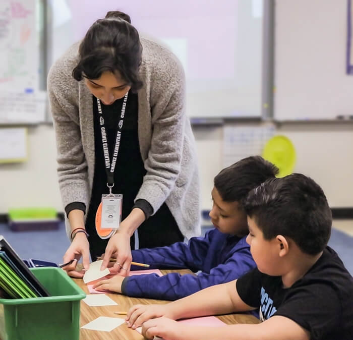 a female student teacher helping two young boys in the classroom